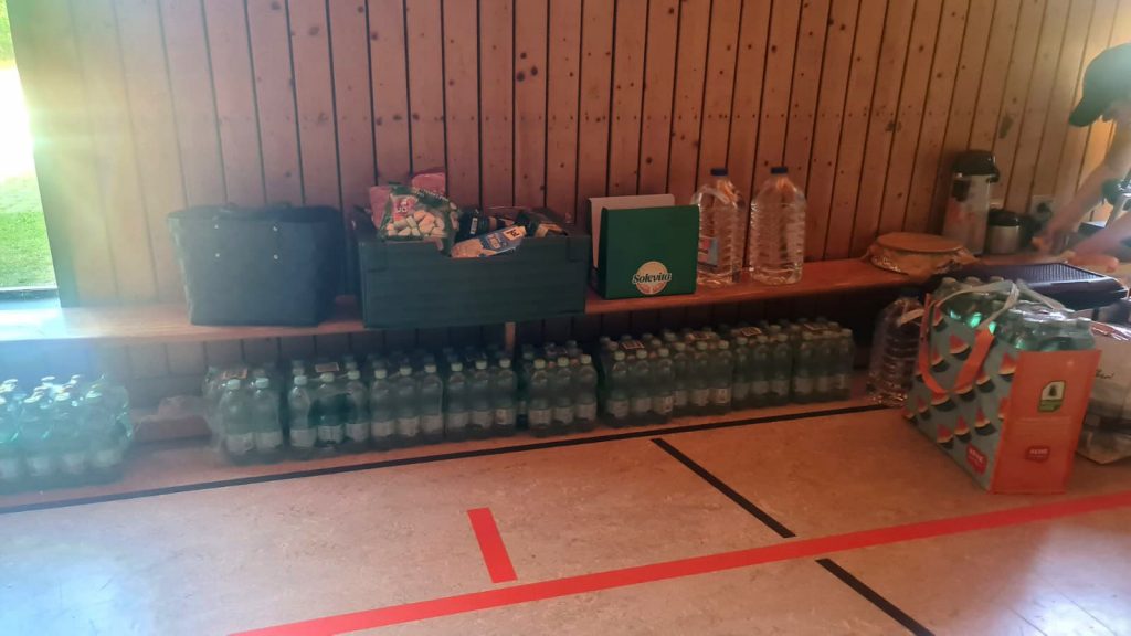 Bereitgestellte Getränke und Snacks lagern in einer schattigen Halle.